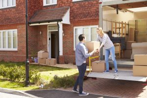 Couple Unpacking Moving In Boxes From Removal Truck